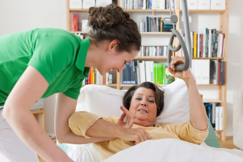 Pflegekraft unterstützt eine ältere Patientin im Bett bei der täglichen Pflege im Rahmen der ambulanten Pflege